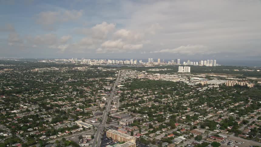 Aerial footage of a sunny suburban area in Sunny Isles Beach Florida featuring distant coastal skyscrapers in the background