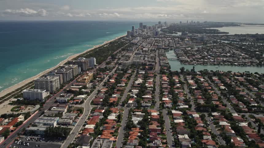 Aerial footage tilting up and flying over coastal residential neighborhoods and seashores in Surfside Florida revealing homes and buildings on the shoreline of southern Florida