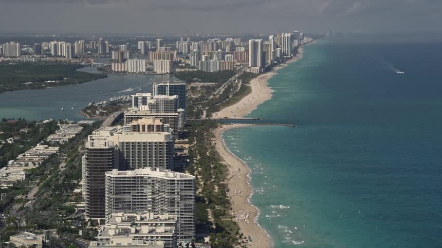 The aerial footage captures the view of beachfront condos and hotels in Bal Harbour and Sunny Isles Beach Florida with partly cloudy skies