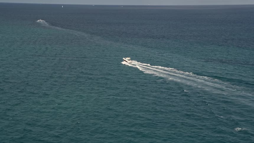 Fishing boats are racing across the blue water of the ocean as an aerial video captures their approach near South Beach Florida