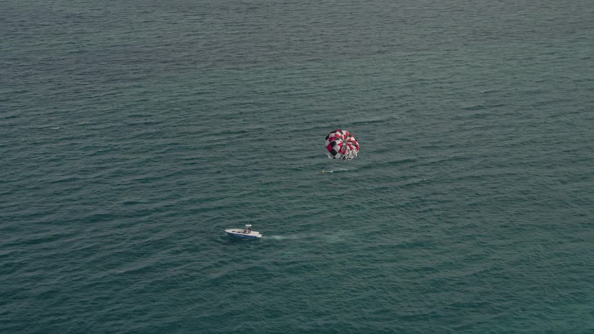 Parasailor gliding over the Atlantic ocean near South Beach Miami seen in 5K aerial stock footage