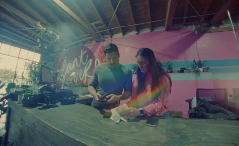 A man and woman add up receipts on a calculator at a plant store