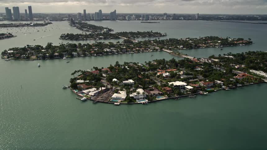 Approaching and flying over luxurious waterfront mansions on one of the Venetian Islands in Southern Florida