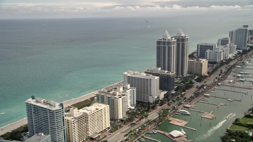 A stunning aerial view of oceanfront hotels and condominiums in the bustling coastal city of Miami Beach Florida with partly cloudy skies