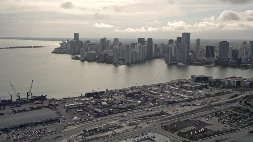 Aerial view of Downtown Miami skyline and Port of Miami with boats in the water and overcast skies