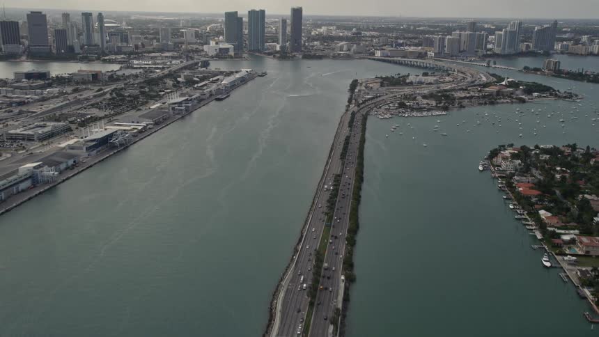 An aerial view of Miamis downtown skyscrapers is revealed as the camera tilts up from the MacArthur Causeway over the coastline and freeway