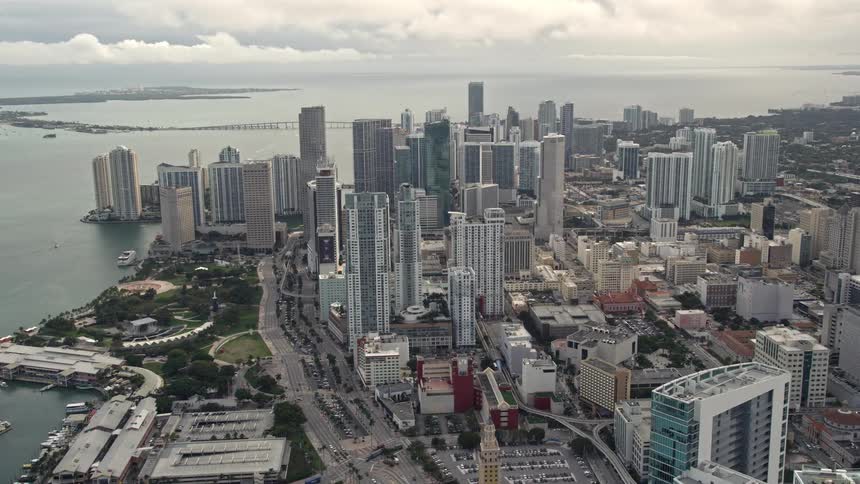 Pan across four skyscrapers to reveal Downtown Miami high-rises on a partly cloudy day in Florida