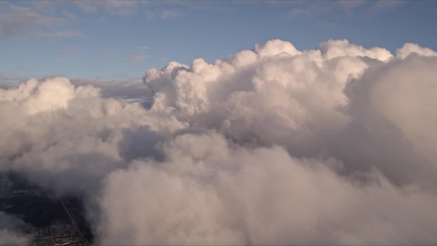 Approaching a thick and cloudy formation at sunset over Miamis coastline viewed in stunning aerial footage during Floridas spring or summer season
