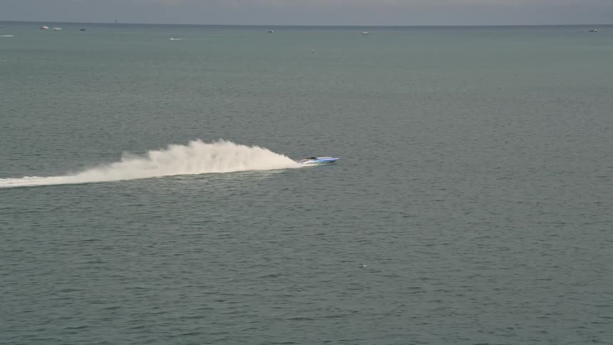 Sport boat races across Biscayne Bay leaving a splashing trail in its wake