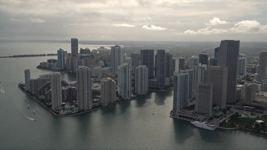 The aerial footage features a tilt-up from the Port of Miami revealing and approaching the high rise buildings of downtown Miami Florida on a cloudy day