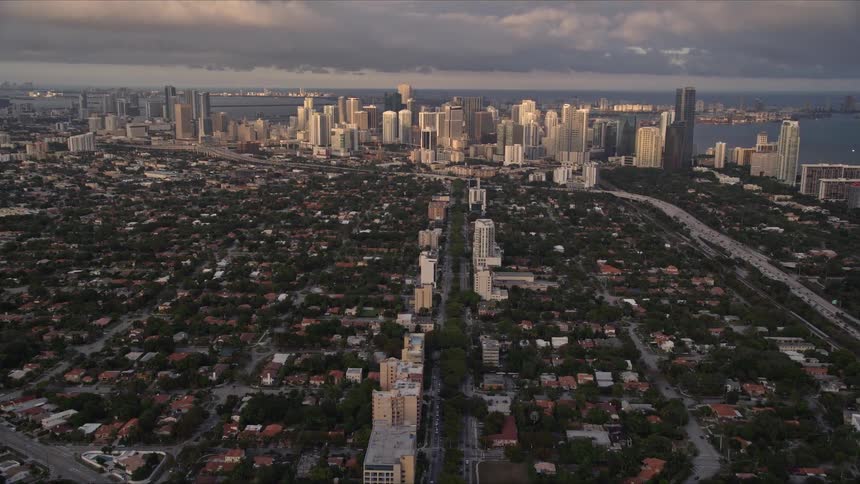 Fly over the suburbs of Miami and approach Downtown at sunset capturing the city skyline and residential neighborhoods