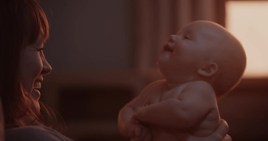 A mother holds up her baby as she talks and plays with them