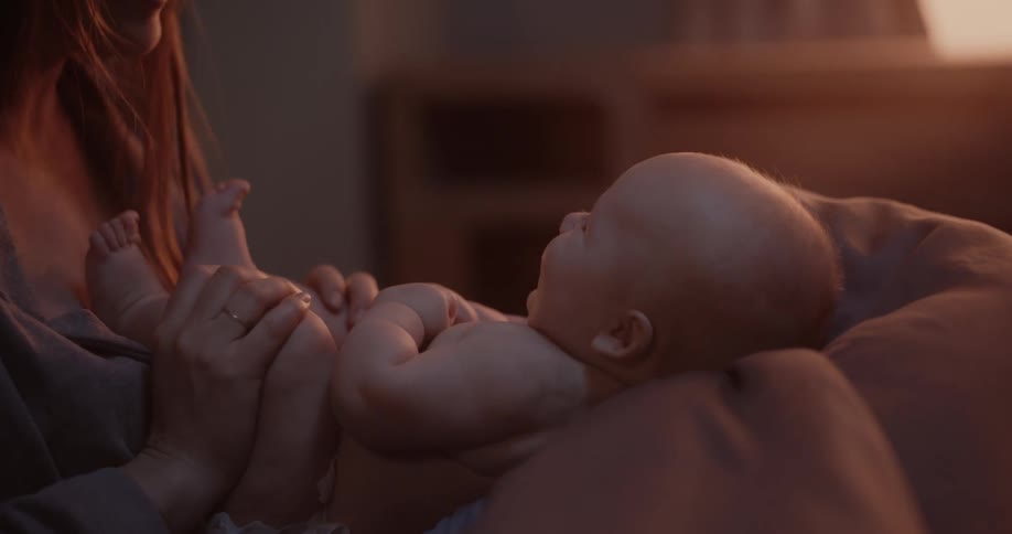 Mother with bangs kisses newborns babys feet laughing