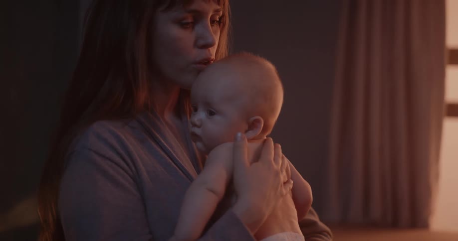 A woman is holding her baby in her arms and gently patting them on the back