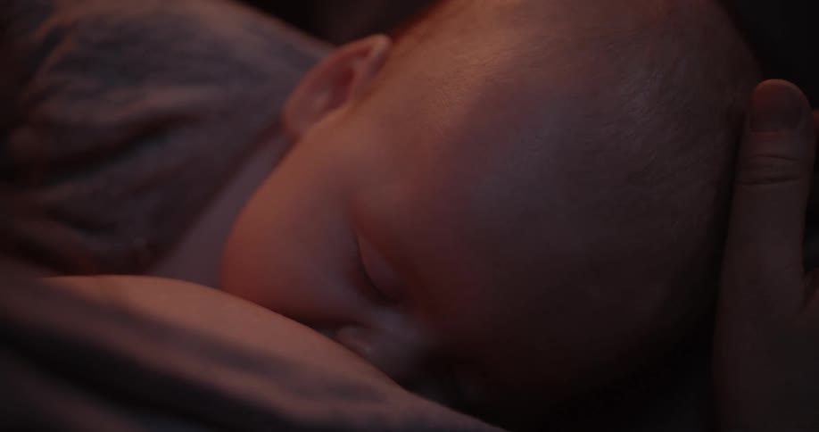 Mother breastfeeds baby and strokes his head