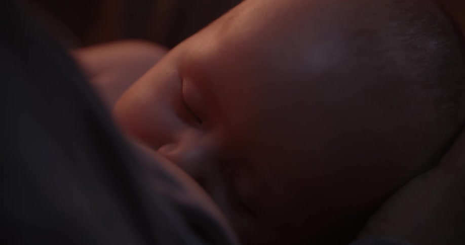 Mother nurses her baby while stroking the head of the child