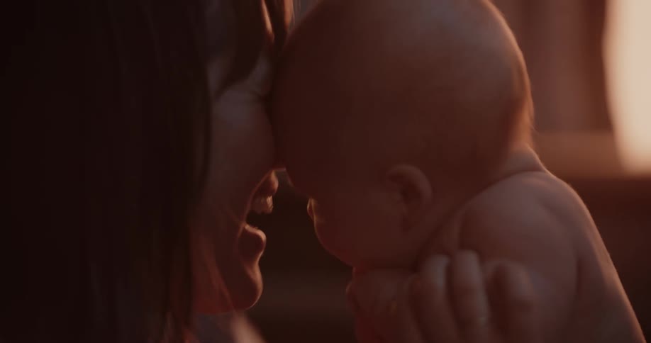 Mom holds newborn baby laughing in room