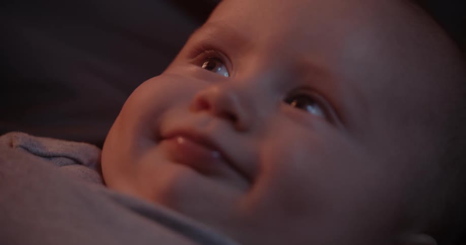 A baby is looking upward and smiling