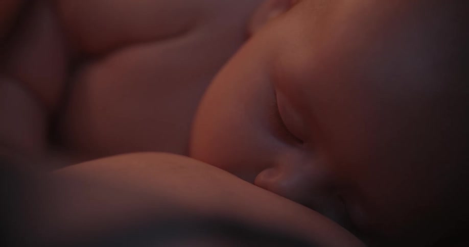 A young baby is snuggled next to its mother while breastfeeding