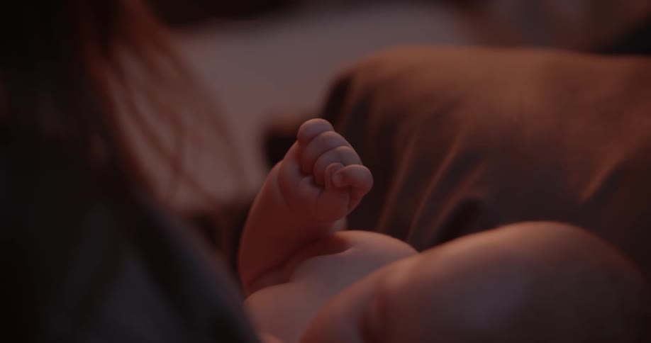 Mother with brown hair breastfeeds newborn baby sleeping