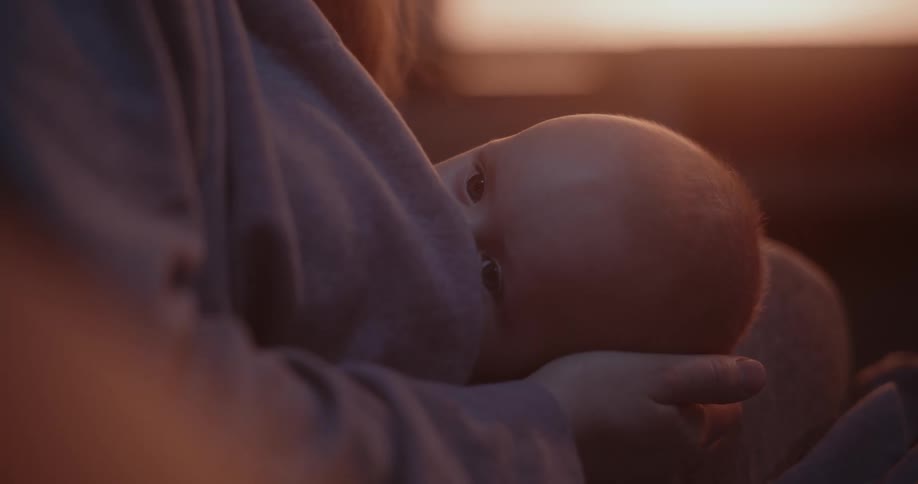 Mother and infant breastfeeding sitting in front of the window in the morning