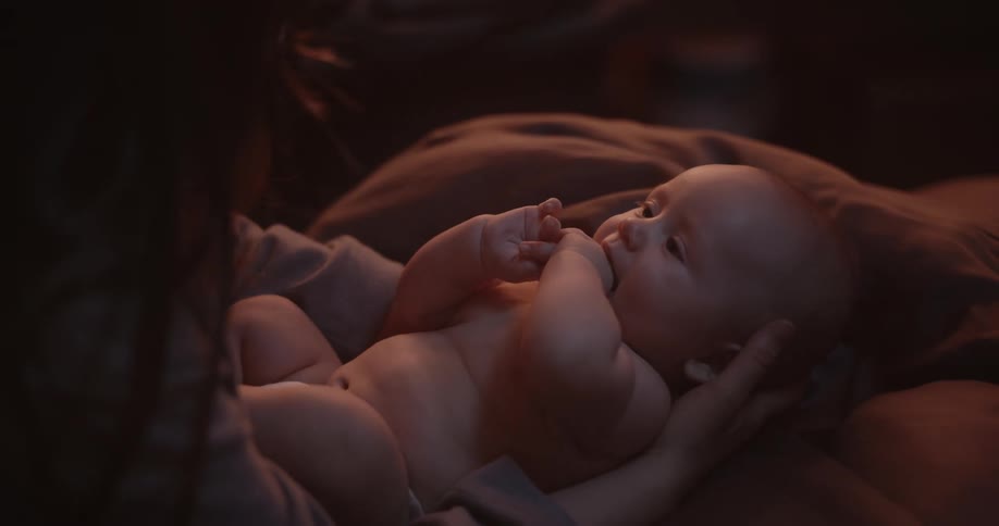 Mother with brown hair holds newborn baby with diaper in her arms