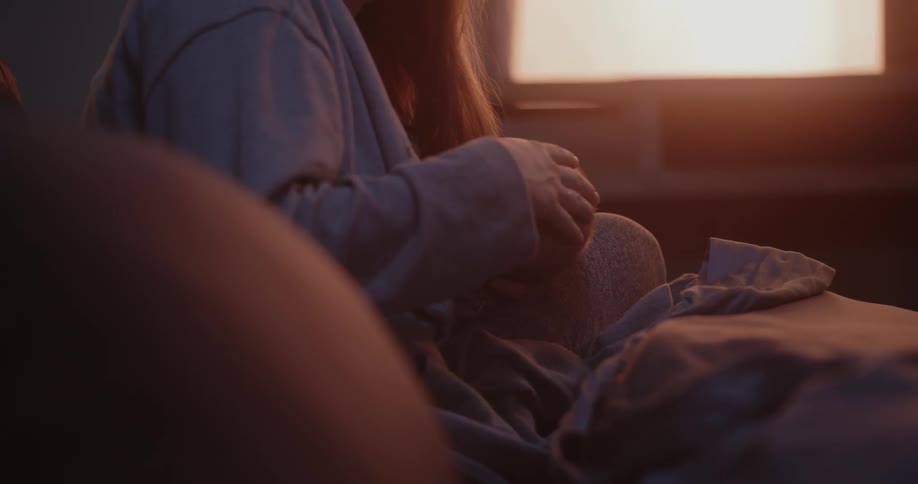 Mother with brown bangs breastfeeds newborn baby in room while the sun shining through windows