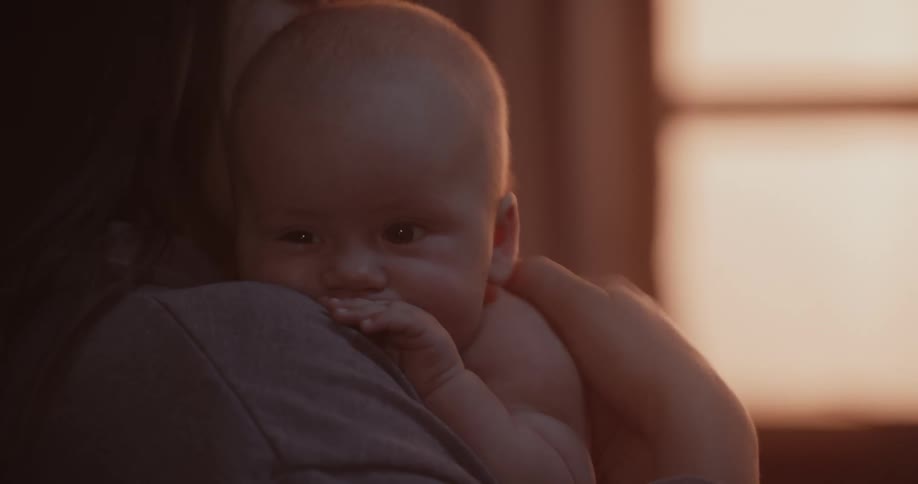 Mother burping infant child over shoulder after nighttime feeding