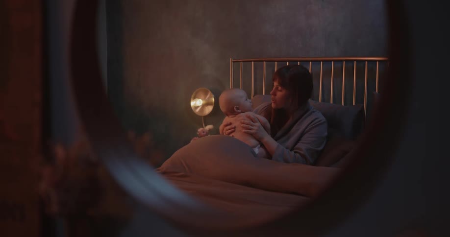 A woman coos at her baby while sitting in bed