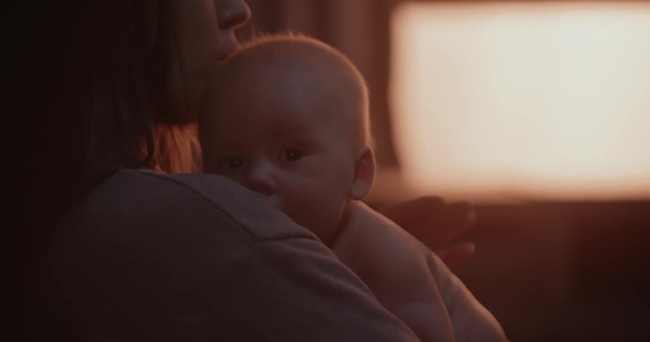 Mother with brown hair holds newborn baby with diaper