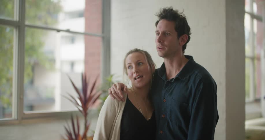 A man puts his arm around his wife while chatting in their apartment