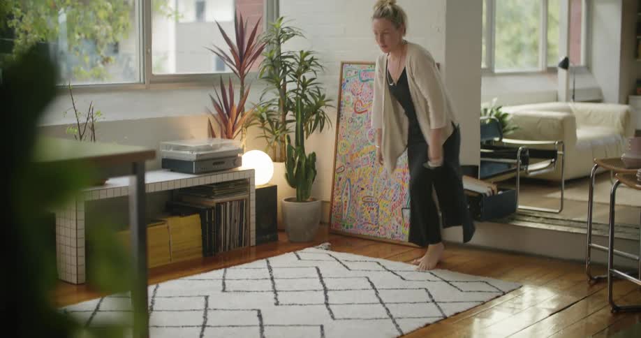 A woman is placing a rug on her floor