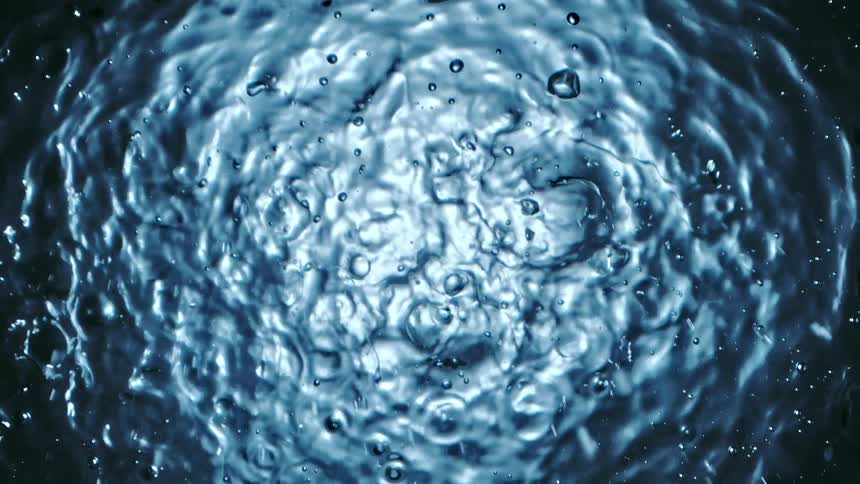 Water dropping into a puddle of water creating ripples on the surface