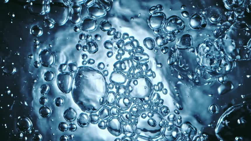 Light shines on clear liquid as bubble spheres move and break apart