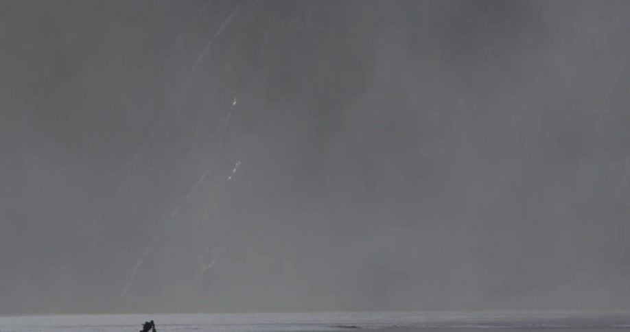 A photographer sets up a tripod near a lake