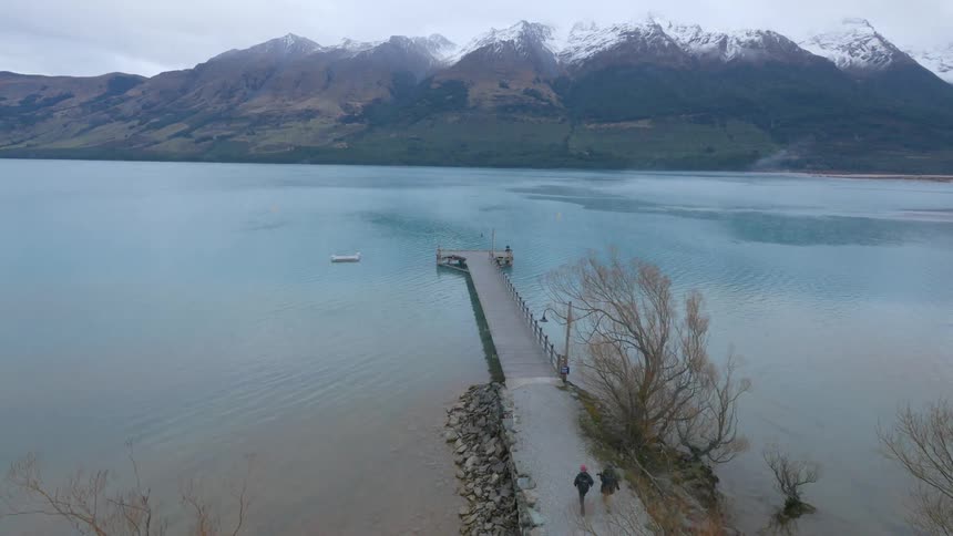 People walking down a long pier on a body of water