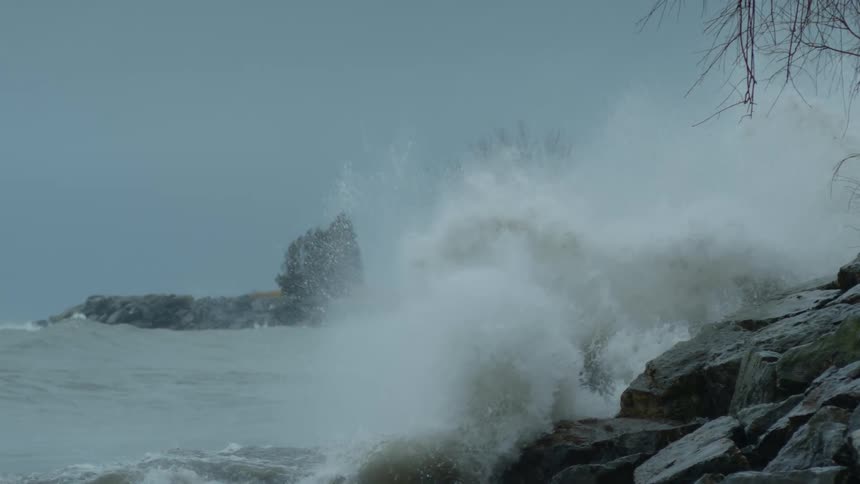 Slow motion footage shows waves crashing upon a rocky shoreline