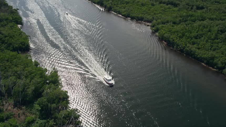 Approaching a fishing boat winding its way through the lush verdant Indian River in Hobe Sound Florida on a sunny day