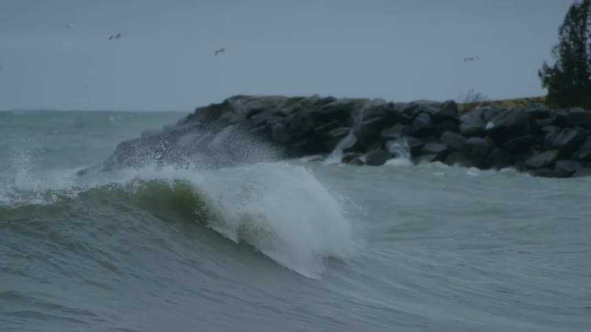 A male surfer attempts to paddle while on his board as a wave passes by