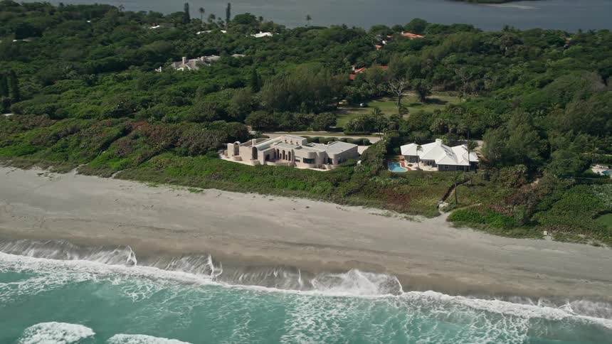 Aerial footage of two luxurious mansions on the beach in Hobe Sound Florida surrounded by sunshine and beautiful ocean views