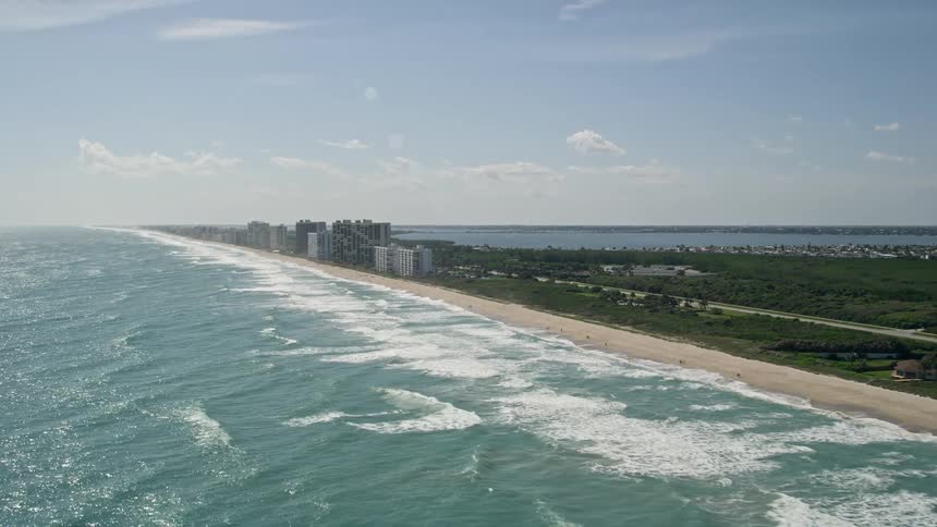 Gorgeous aerial footage of bustling apartment buildings lining Jensen Beach Floridas sunny coastline offering a range of entertainment and recreation options for beachgoers and tourists alike
