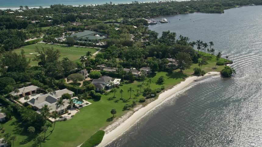 Stunning aerial view of luxurious waterfront mansions in Hobe Sound Florida surrounded by palm trees and the sunshine