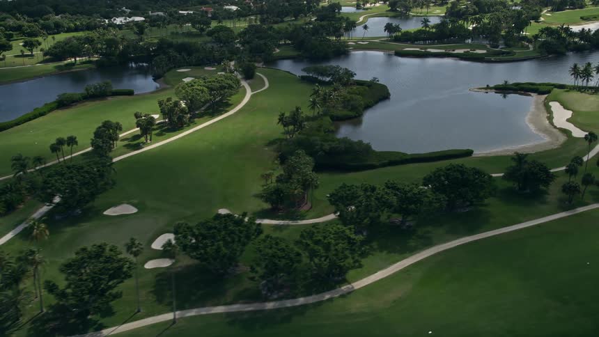 A stunning aerial view of Jupiter Island Golf Club a tropical golf course surrounded by palm trees lakes and ponds in Hobe Sound Florida