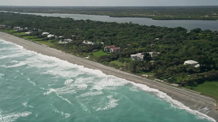 Tilting up an aerial view reveals luxurious beachfront mansions in the exclusive Hobe Sound neighborhood of Martin County Florida