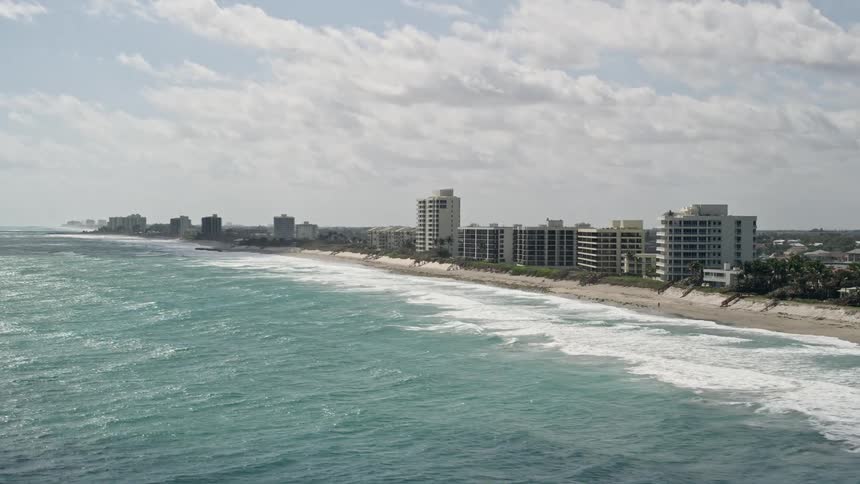 Aerial footage of beachfront apartment buildings in Tequesta Florida offering a stunning view of the oceanfront property and surrounding metropolitan areas