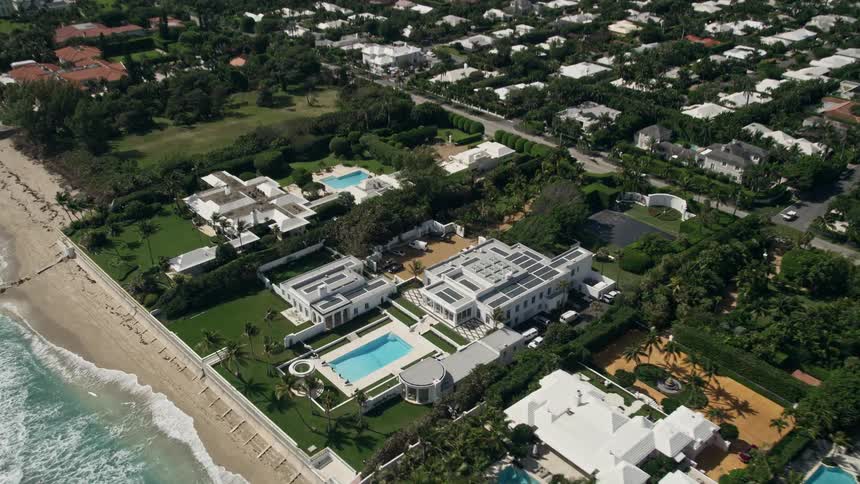 An aerial view of luxurious oceanfront mansions in Palm Beach Florida with a tilt-down to showcase the waterfront property