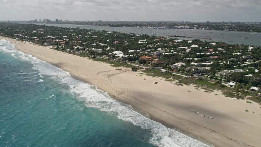 An aerial view of Palm Beach Floridas coastal neighborhoods and beaches with partly cloudy skies and no people