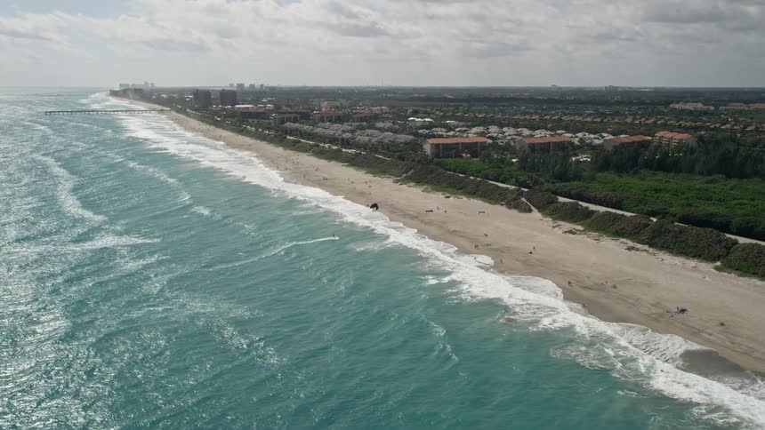 Approaching one daring kite surfer while capturing the stunning Florida coastline and suburban neighborhood through 5k aerial video footage in Jupiter on a sunny day