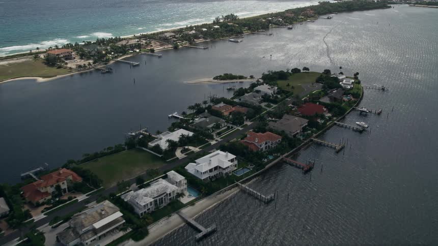 A breathtaking drone flyover of a Manalapan island with lavish waterfront mansions and piers to dock boats