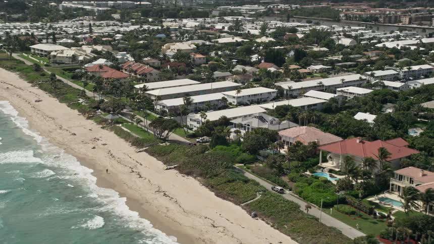 A stunning 5K aerial view of the Ocean Ridge coastal community with a tilting motion towards the apartment buildings in Floridas east coast